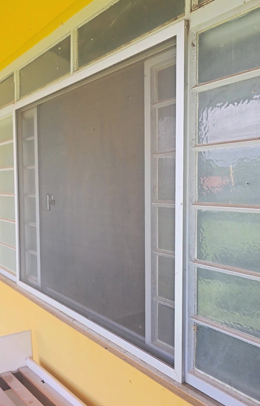 A mesma tela mosquiteira de correr no fim da limpeza: a malha ficou limpa e transparente, só com espanador, numa casa ainda em obra