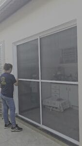 Porta de correr de tela mosquiteira com duas folhas brancas fechando o vão inteiro da porta da cozinha, em Piracicaba