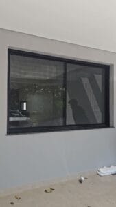 Janela grande de perfil preto com quadro de tela mosquiteira feito sob medida e já instalado, em Piracicaba
