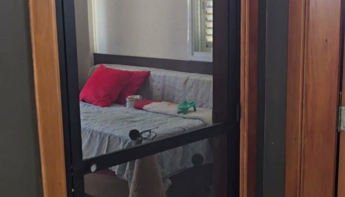Porta de tela com malha pet em esquadria de alumínio preto, fechada no vão de um quarto